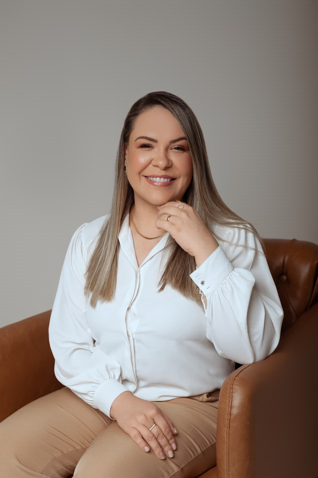 Fabiana Baroni Fuzita sentada em uma poltrona, sorrindo